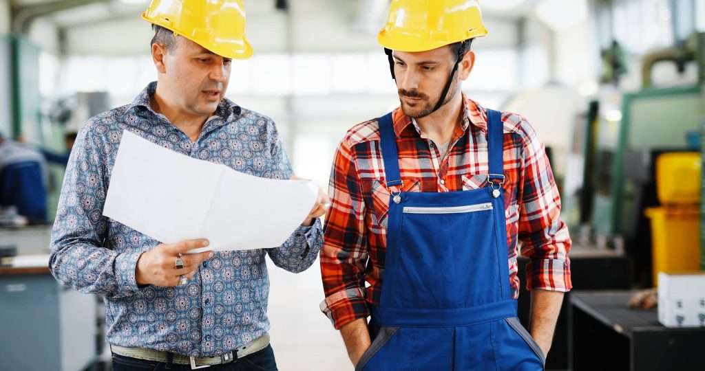 Factory worker discussing data with supervisor in metal industry factory