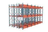 High-density pushback pallet racking system with multiple deep lanes of orange rails on blue uprights.
